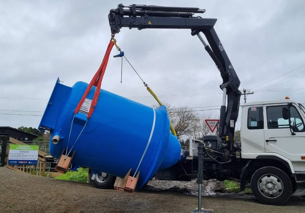 Crane truck lifting and delivering large water tank