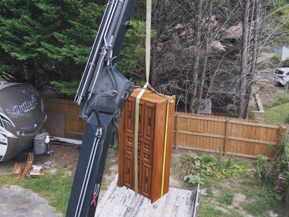 Waste removal service in Asheville area with crane truck and flatbed lifting furniture and heavy items