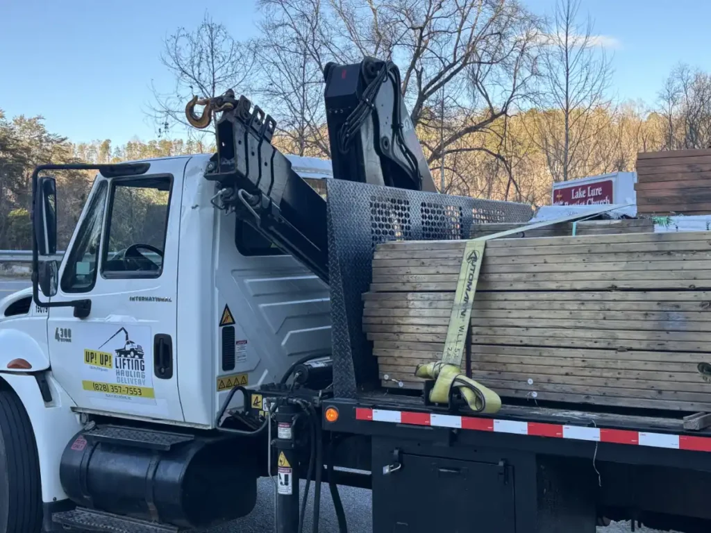 crane truck transporting building supplies in Lake Lure NC for construction contractor job, including bunks of lumber